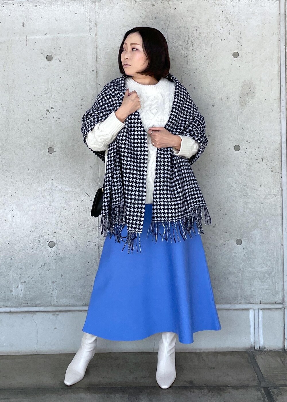 ブラック系のショルダーバッグ、ホワイト系のブーツ、ブルー系のスカートを着用したレディースの秋コーディネートの4枚目の写真