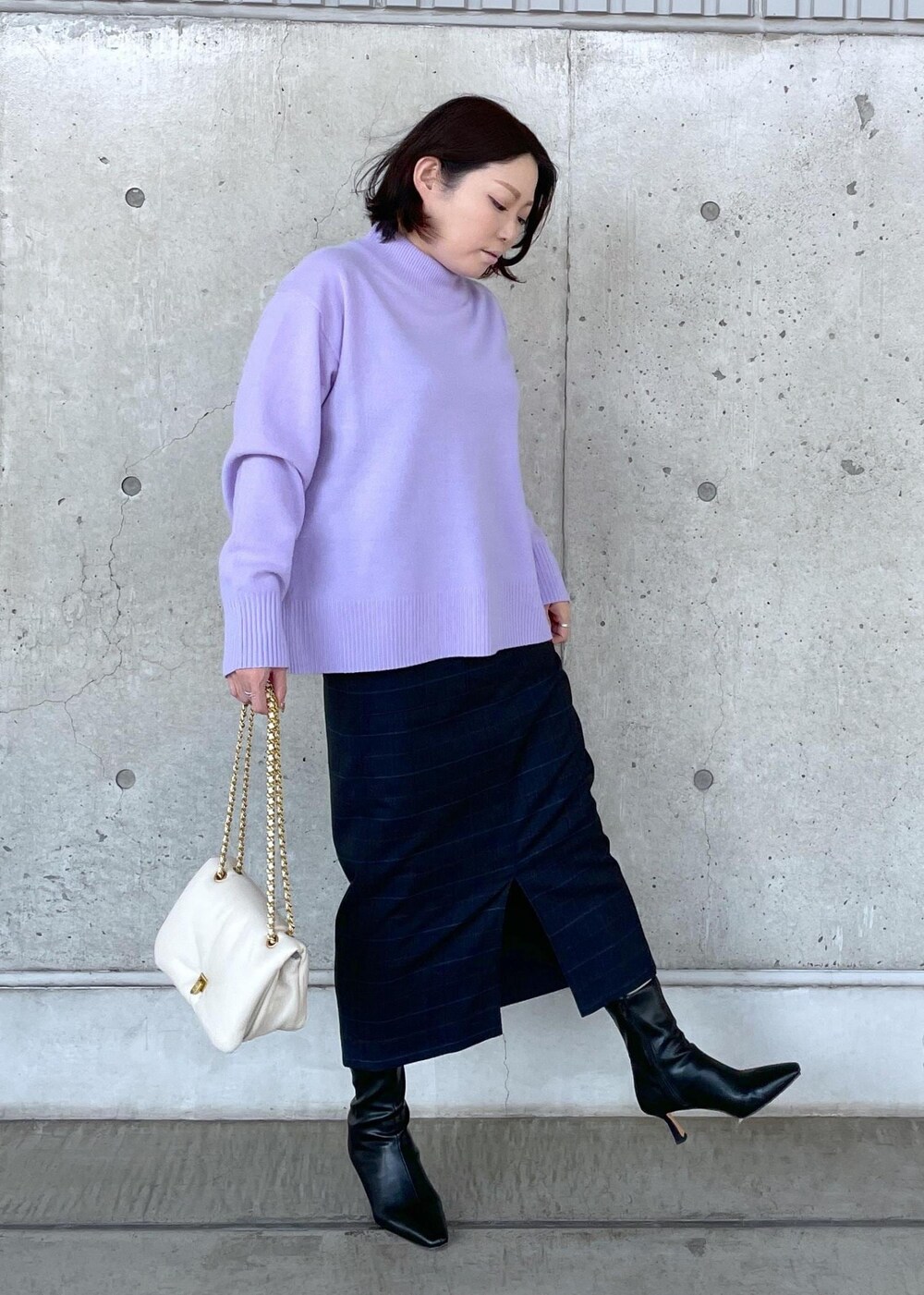 ブラック系のブーツ、ホワイト系のハンドバッグ、ブルー系のスカートを着用したレディースの秋コーディネートの2枚目の写真