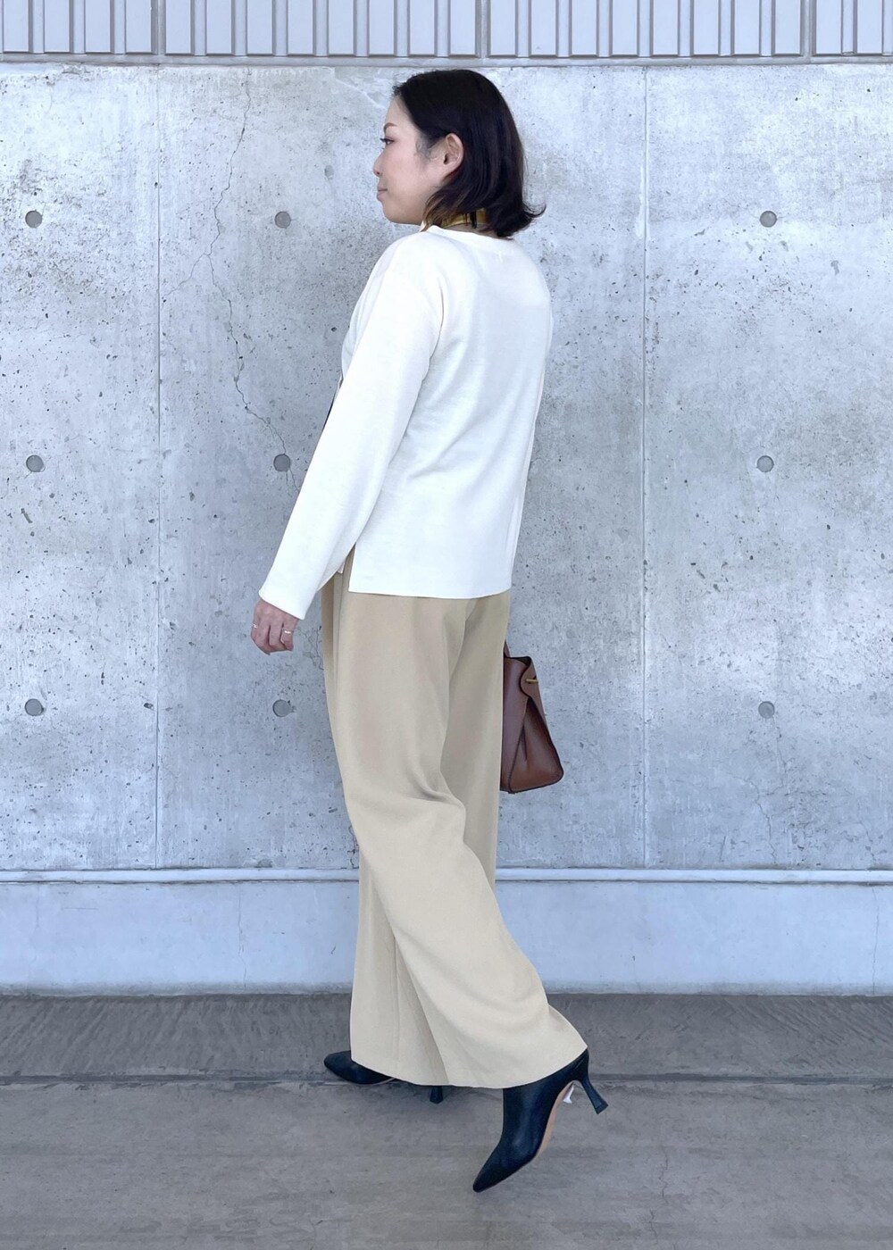ブラック系のブーツ、ベージュ系のその他パンツ、イエロー系のトートバッグを着用したレディースの秋コーディネートの4枚目の写真