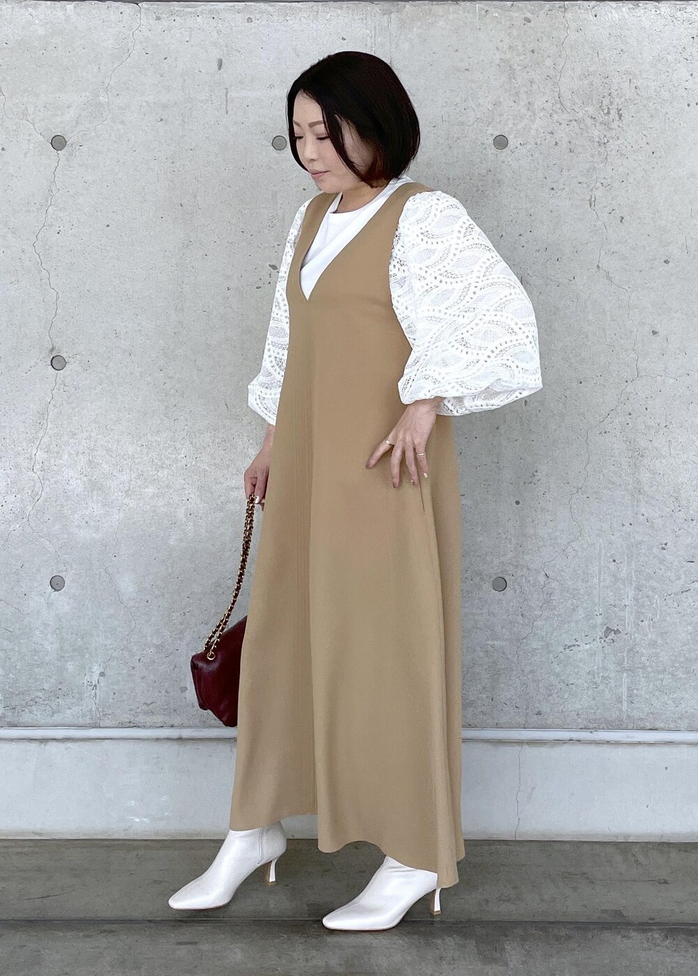 ホワイト系のブーツ、レッド系のハンドバッグ、ベージュ系のジャンパースカートを着用したレディースの秋コーディネートの3枚目の写真