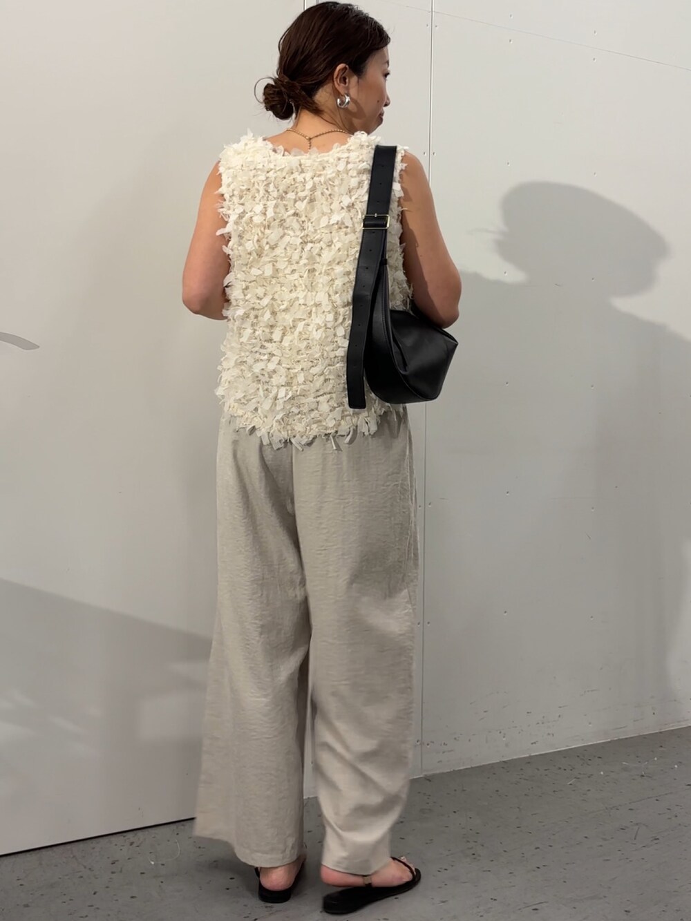 グレー系のその他パンツ、ホワイト系のベスト、ベージュ系のベルトを着用したレディースの夏コーディネートの2枚目の写真