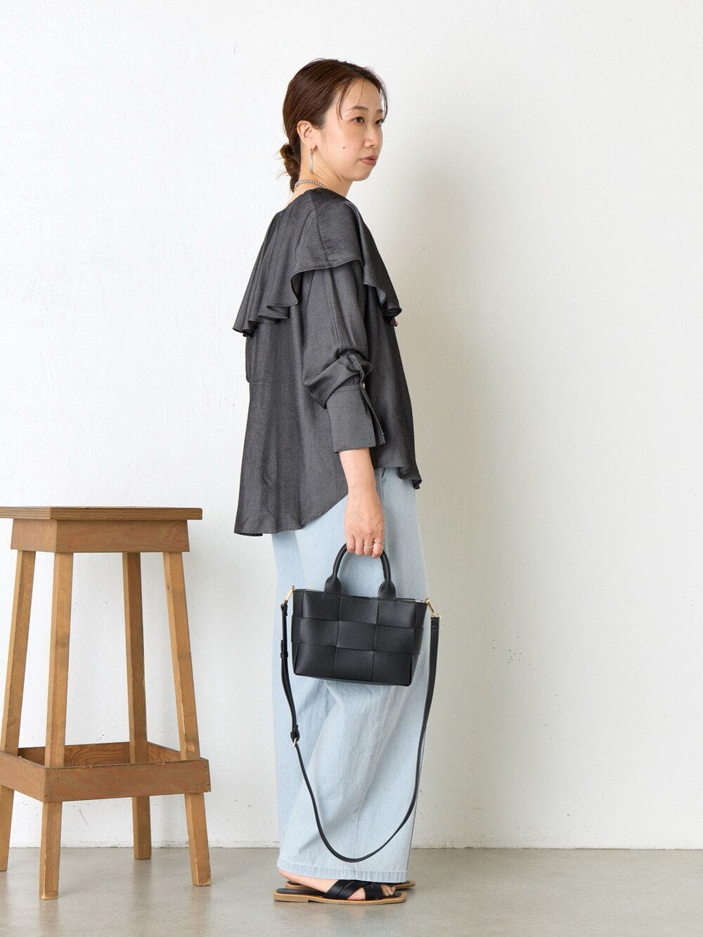 ブラック系のシャツ/ブラウス、ブラック系のトートバッグ、ブルー系のデニムパンツを着用したレディースの夏コーディネートの2枚目の写真