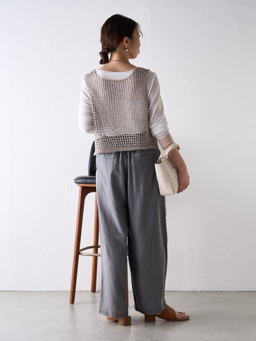 グレー系のニット/セーター、ホワイト系のTシャツ/カットソー、グレー系のその他パンツを着用したレディースの春コーディネートの2枚目の写真