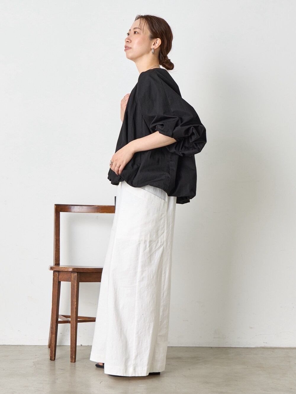 ホワイト系のワンピース、ブラック系のサンダル、ブラック系のベストを着用したレディースの夏コーディネートの2枚目の写真