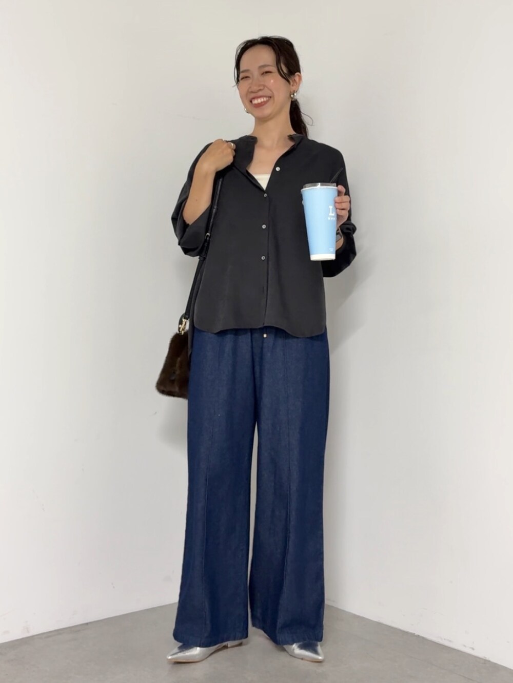 ブラック系のシャツ/ブラウス、ブルー系のデニムパンツ、ブラウン系のトートバッグを着用したレディースの秋コーディネートの2枚目の写真