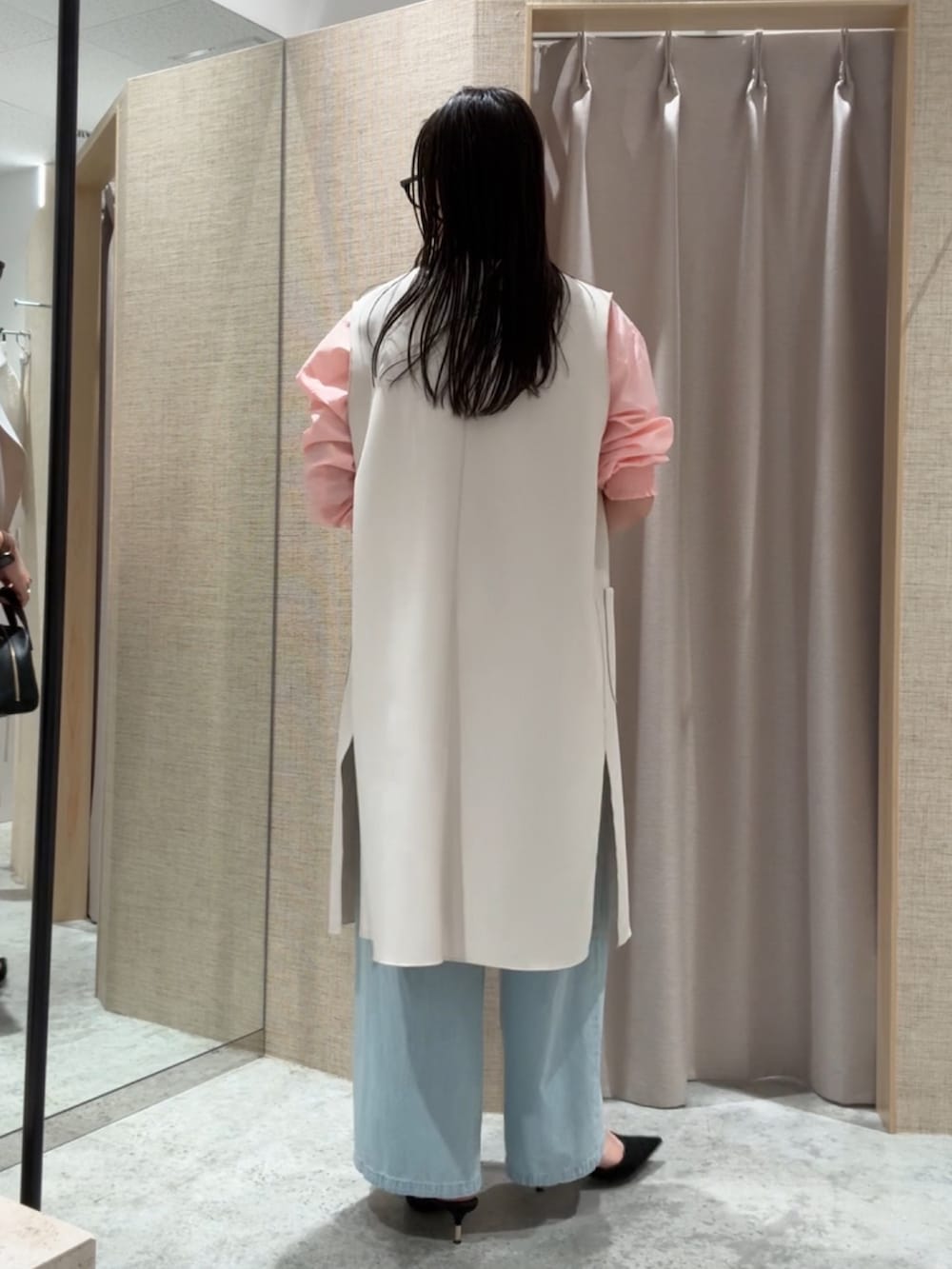 ベージュ系のベスト、ピンク系のシャツ/ブラウス、ブルー系のデニムパンツを着用したレディースの春コーディネートの2枚目の写真