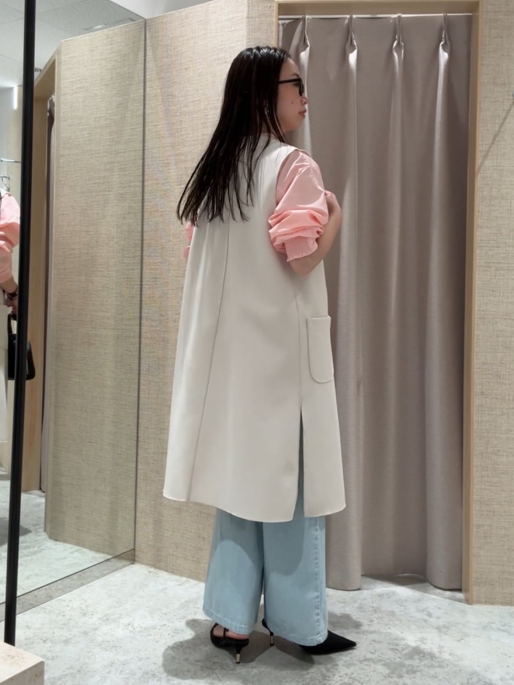 ベージュ系のベスト、ピンク系のシャツ/ブラウス、ブルー系のデニムパンツを着用したレディースの春コーディネートの3枚目の写真