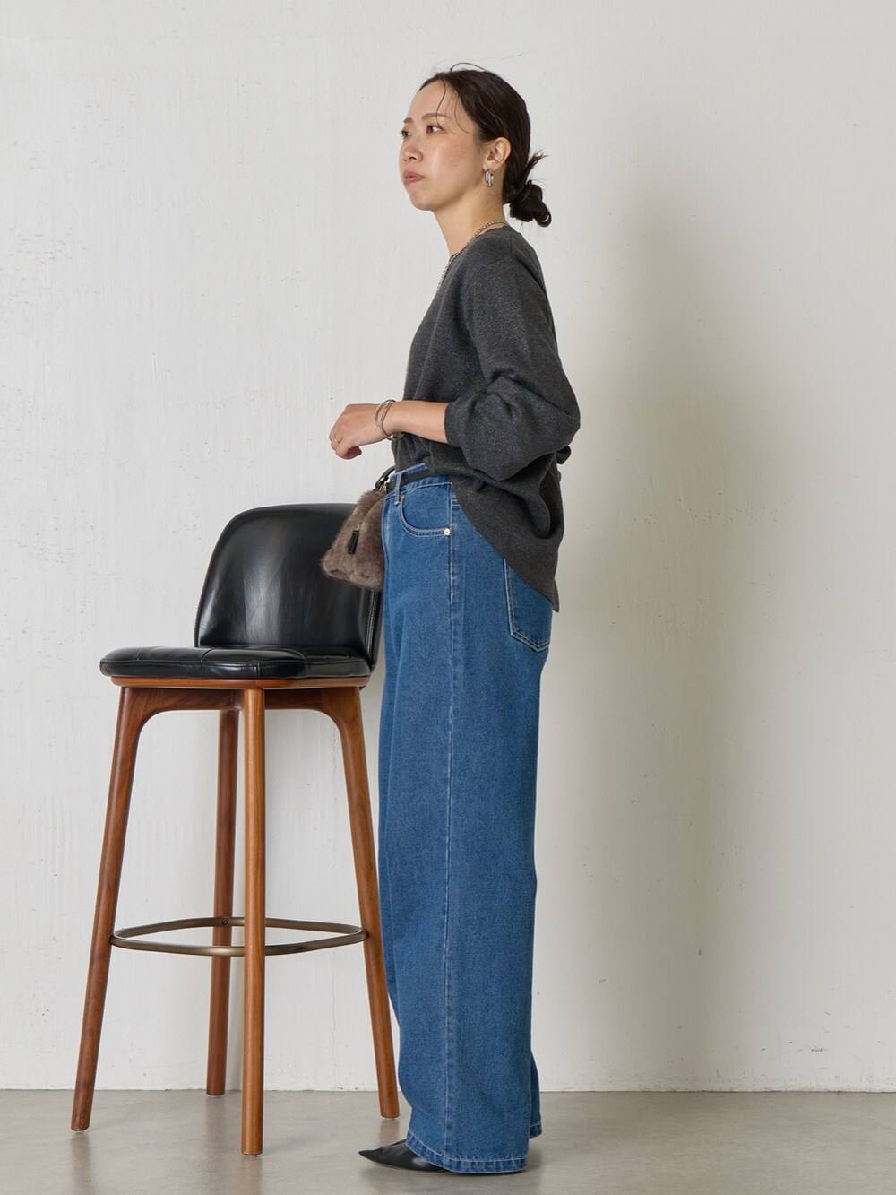 グレー系のニット/セーター、ブルー系のデニムパンツ、グレー系のトートバッグを着用したレディースの秋コーディネートの2枚目の写真