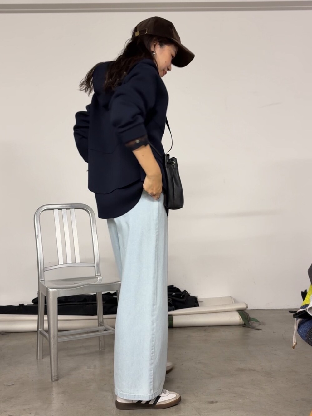 ブルー系のデニムパンツ、ブラック系のトートバッグ、ブルー系のパーカーを着用したレディースの秋コーディネートの2枚目の写真