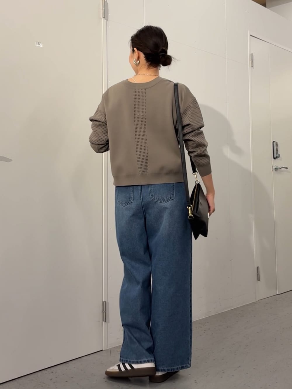 ブルー系のデニムパンツ、ブラック系のトートバッグ、グレー系のカーディガン/ボレロを着用したレディースの冬コーディネートの2枚目の写真