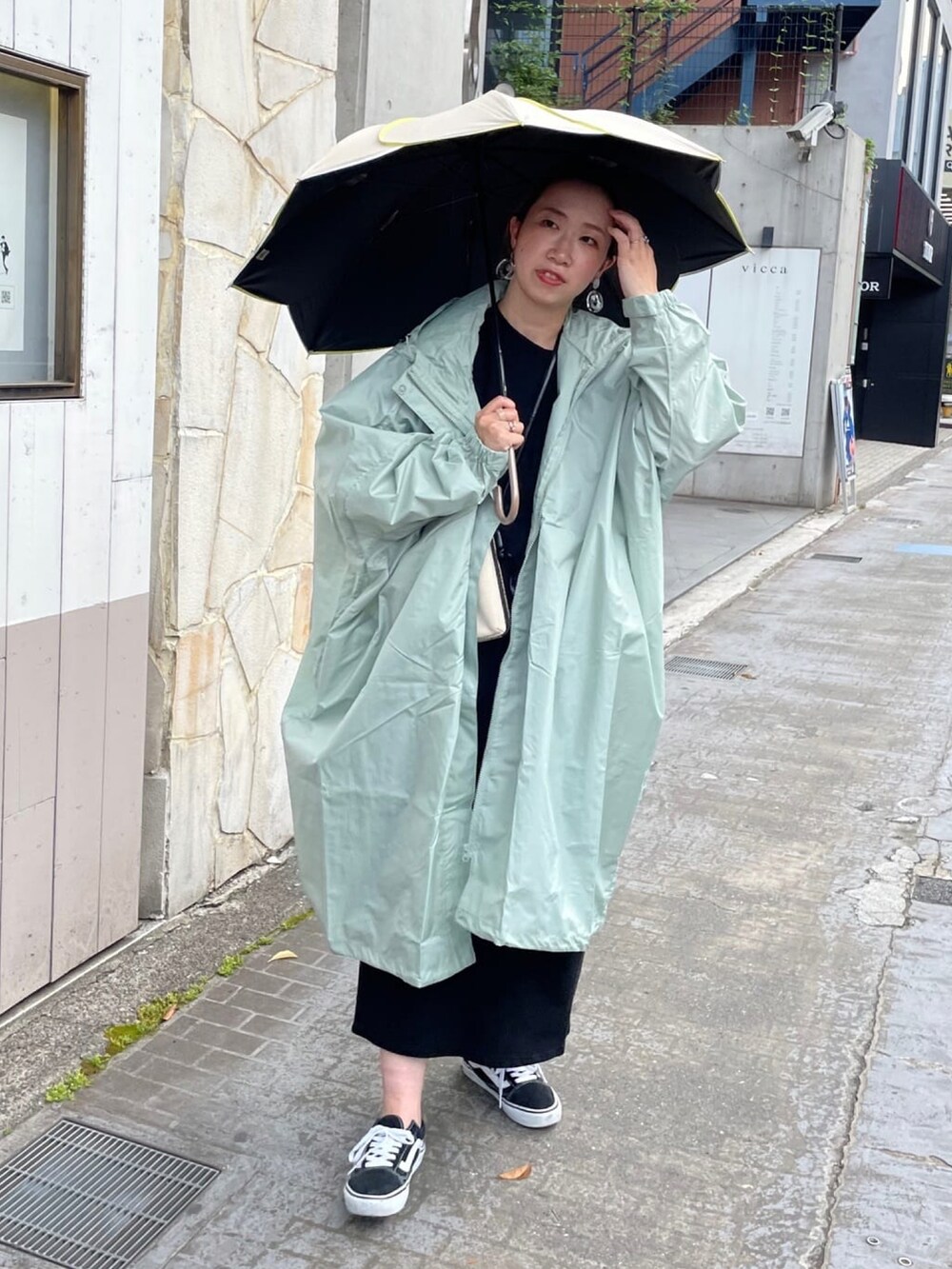 ブラック系のワンピース、ブラック系のショルダーバッグ、グリーン系のマウンテンパーカーを着用したレディースの夏コーディネートの4枚目の写真