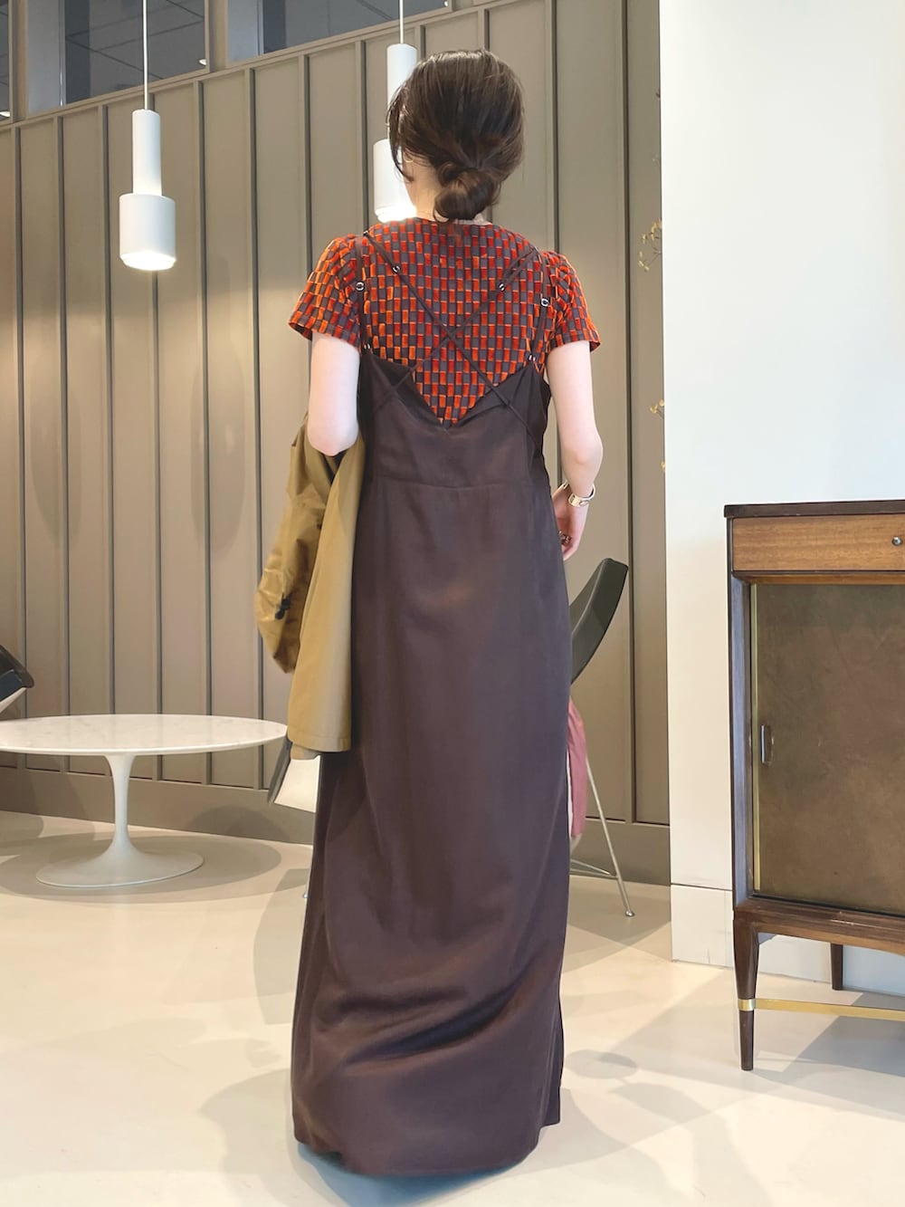 ブラウン系のワンピース、ブラック系のポンチョ、オレンジ系のTシャツ/カットソーを着用したレディースの春コーディネートの2枚目の写真