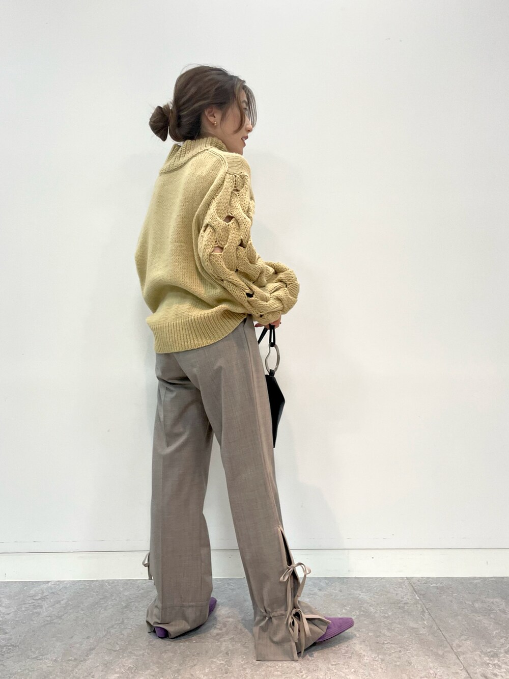 ベージュ系のニット/セーター、グレー系のパンツ、ブラック系のトートバッグを着用したレディースの秋コーディネートの2枚目の写真