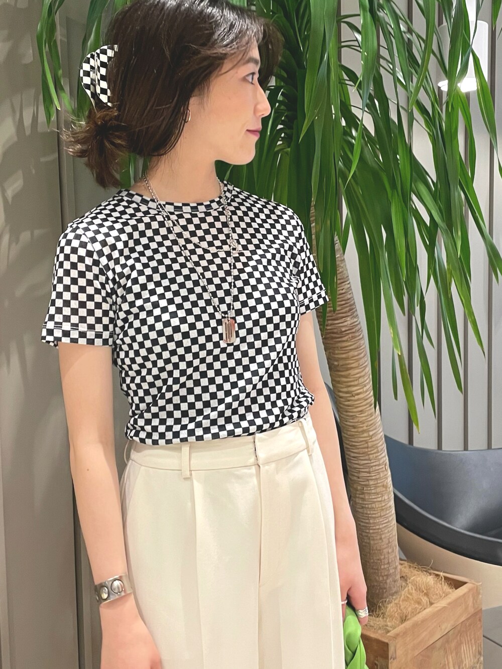 ブラック系のTシャツ/カットソー、グリーン系のトートバッグ、ブラック系のパンプスを着用したレディースの春コーディネートの2枚目の写真