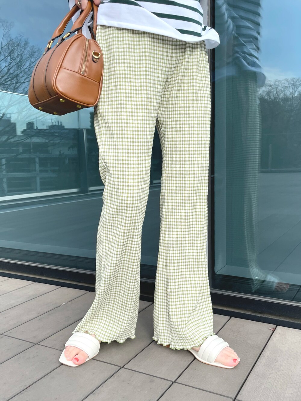 グリーン系のTシャツ/カットソー、ブラウン系のボストンバッグ、ホワイト系のサンダルを着用したレディースの春コーディネートの5枚目の写真