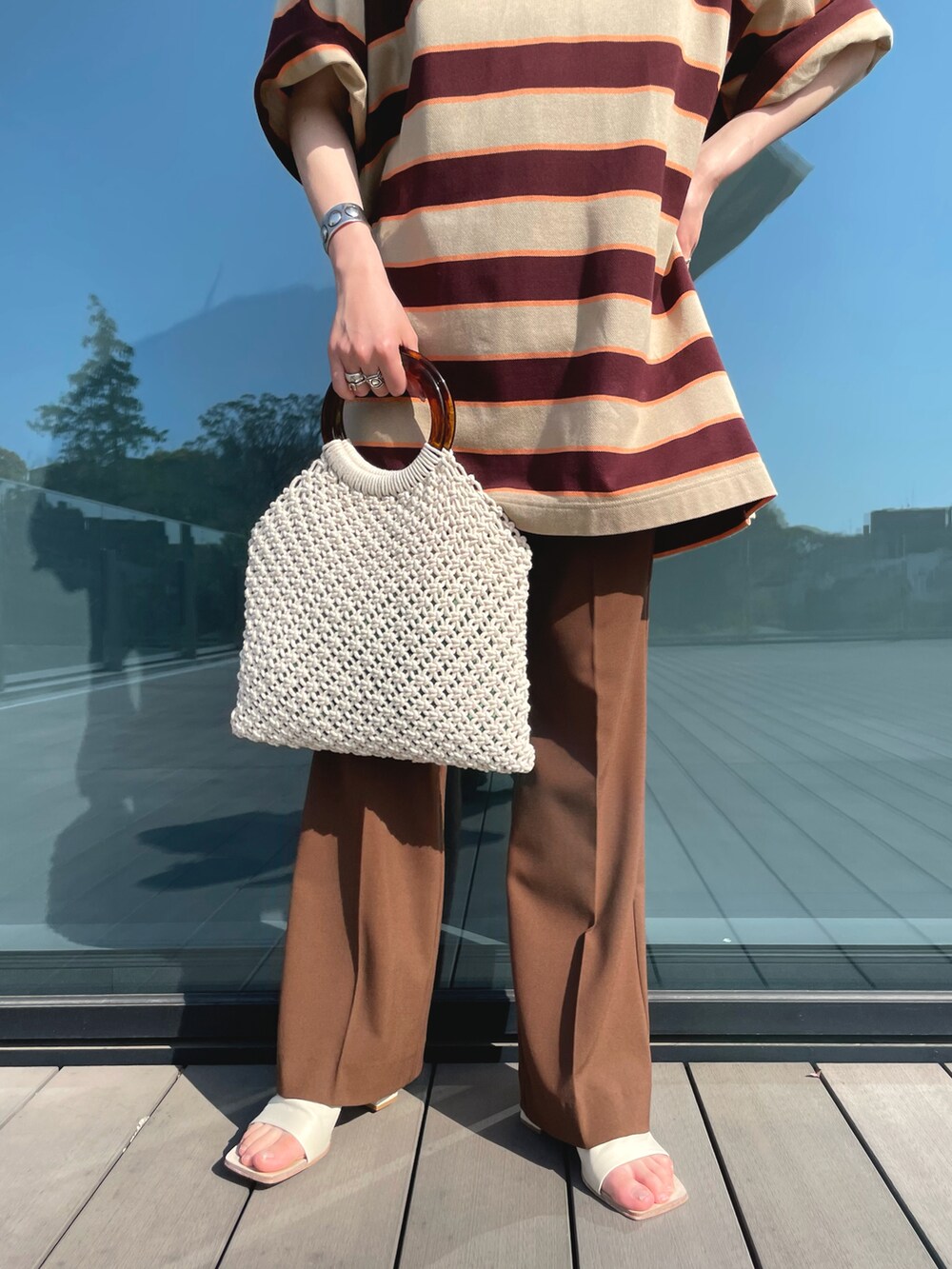 ベージュ系のTシャツ/カットソー、ブラウン系のその他パンツ、ホワイト系のかごバッグを着用したレディースの春コーディネートの3枚目の写真