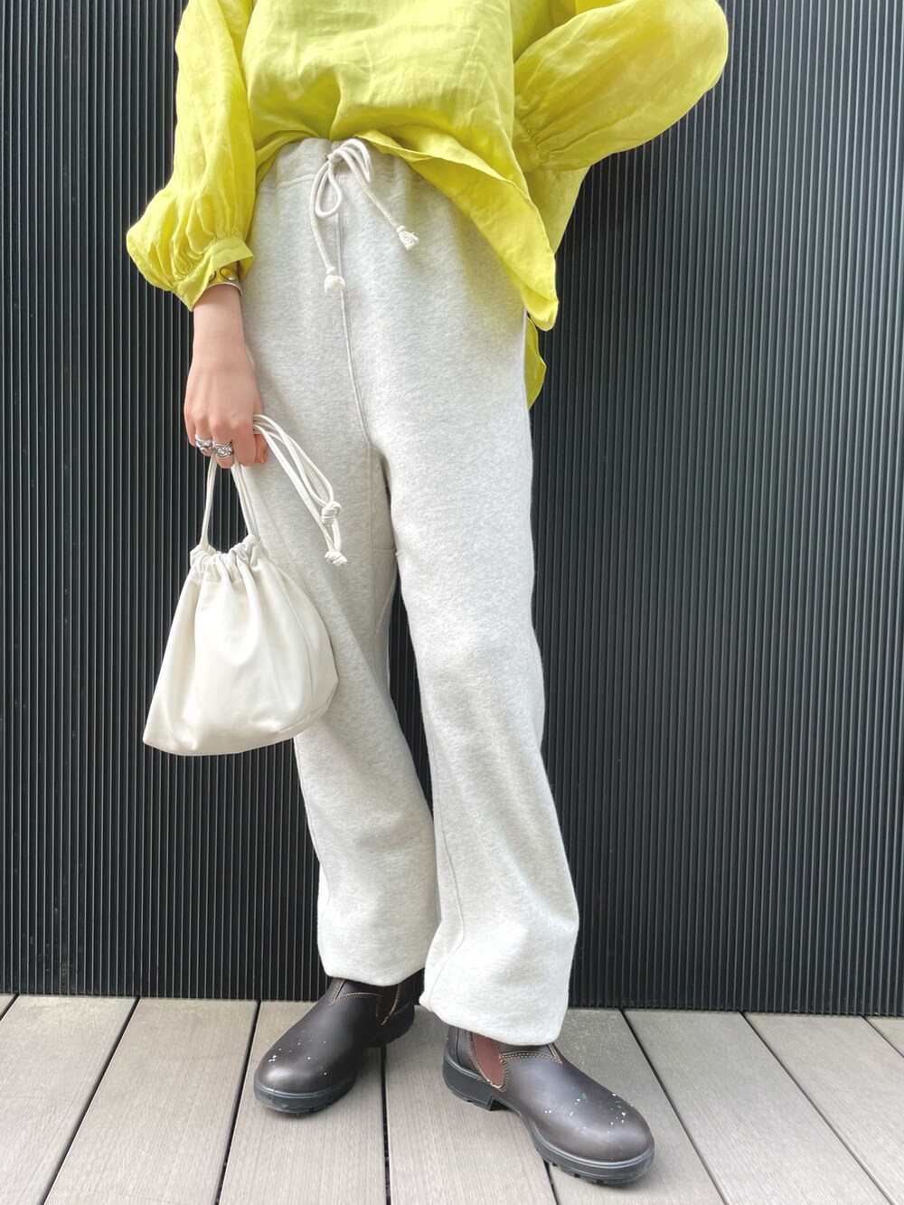 イエロー系のシャツ/ブラウス、ホワイト系のバッグ、ブラウン系のレインシューズを着用したレディースの春コーディネートの4枚目の写真