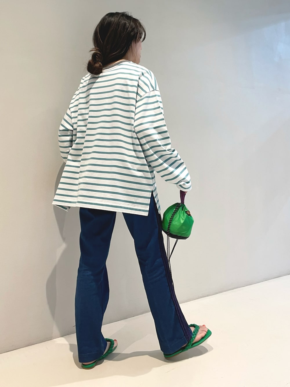 グリーン系のTシャツ/カットソー、グリーン系のトートバッグ、ブルー系のデニムパンツを着用したレディースの春コーディネートの4枚目の写真