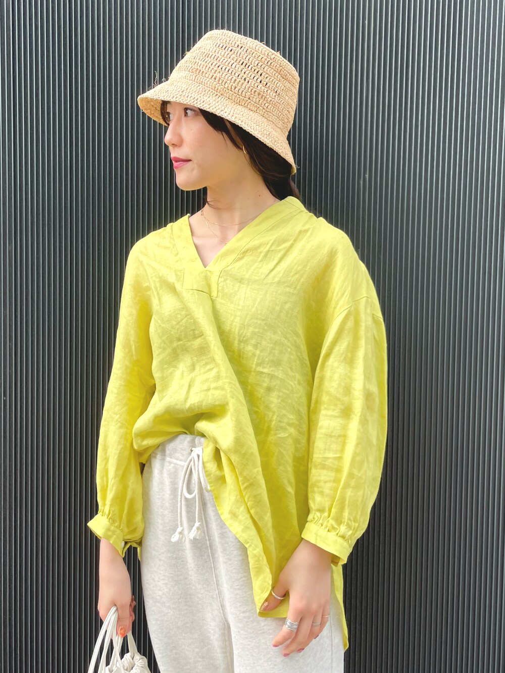 イエロー系のシャツ/ブラウス、ホワイト系のバッグ、ブラウン系のレインシューズを着用したレディースの春コーディネートの3枚目の写真