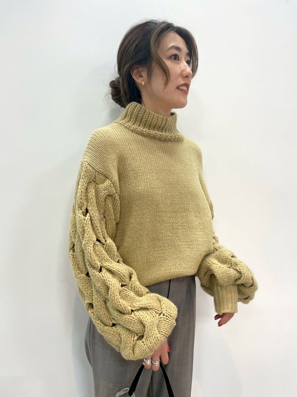 ベージュ系のニット/セーター、グレー系のパンツ、ブラック系のトートバッグを着用したレディースの秋コーディネートの3枚目の写真