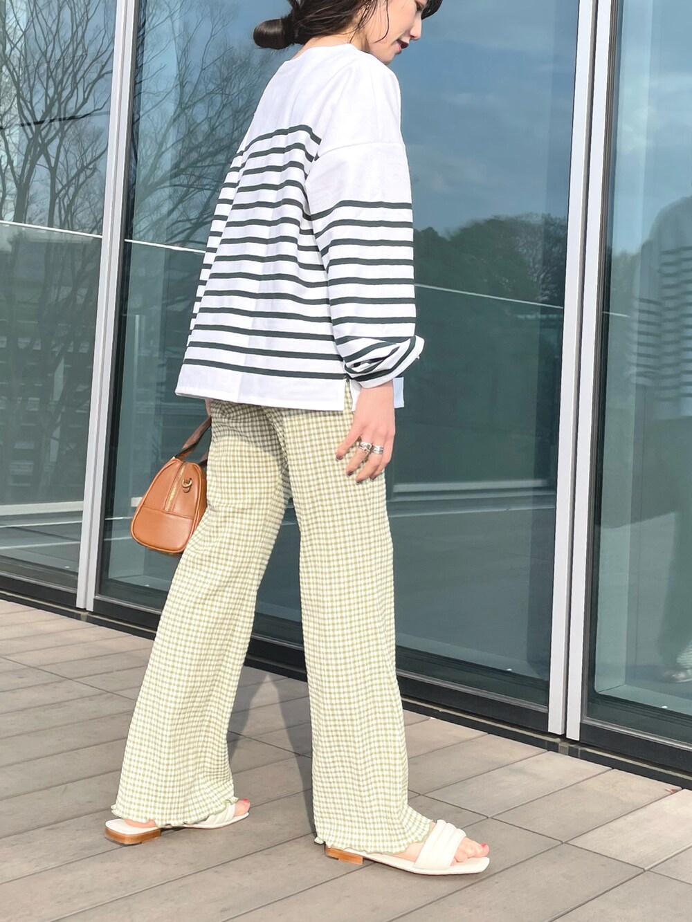 グリーン系のTシャツ/カットソー、ブラウン系のボストンバッグ、ホワイト系のサンダルを着用したレディースの春コーディネートの2枚目の写真