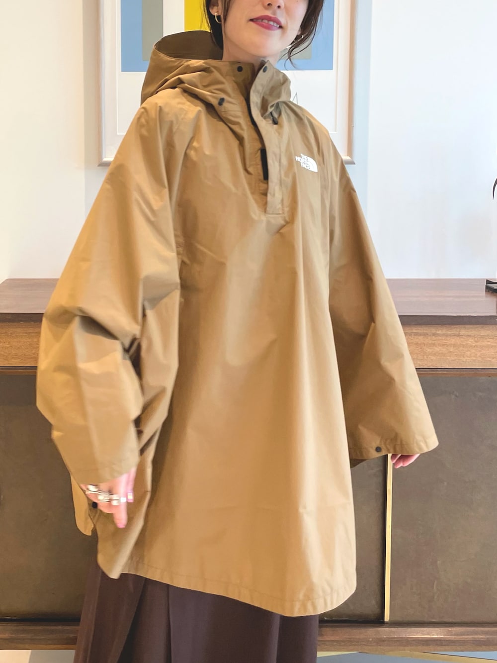 ブラウン系のワンピース、ブラック系のポンチョ、オレンジ系のTシャツ/カットソーを着用したレディースの春コーディネートの5枚目の写真