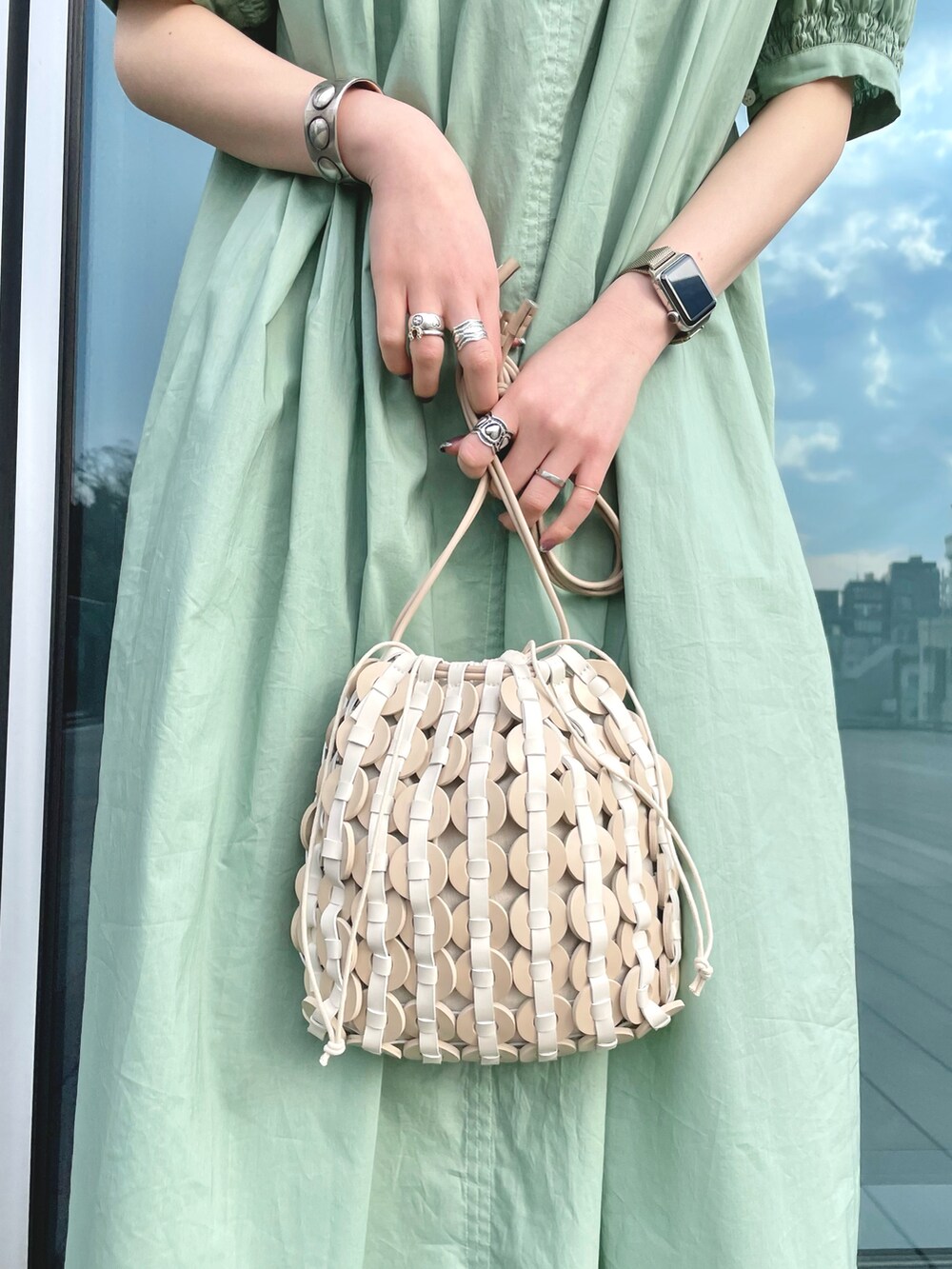 ベージュ系のハンドバッグ、イエロー系のサンダル、グリーン系のワンピースを着用したレディースの春コーディネートの5枚目の写真