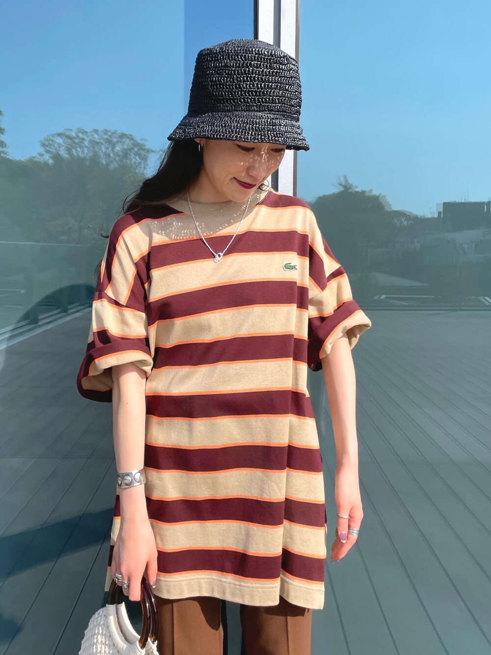 ベージュ系のTシャツ/カットソー、ブラウン系のその他パンツ、ホワイト系のかごバッグを着用したレディースの春コーディネートの2枚目の写真