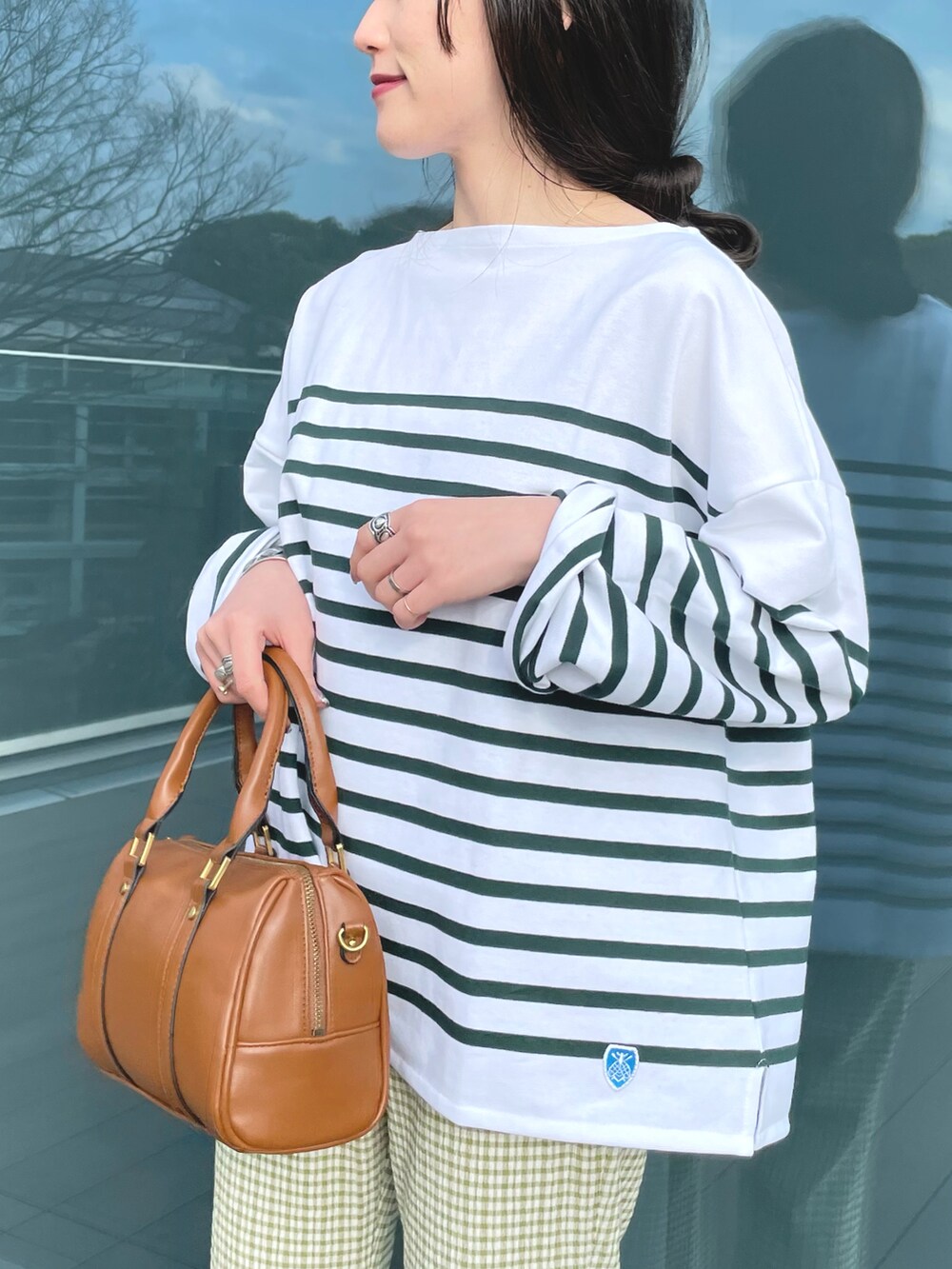 グリーン系のTシャツ/カットソー、ブラウン系のボストンバッグ、ホワイト系のサンダルを着用したレディースの春コーディネートの3枚目の写真