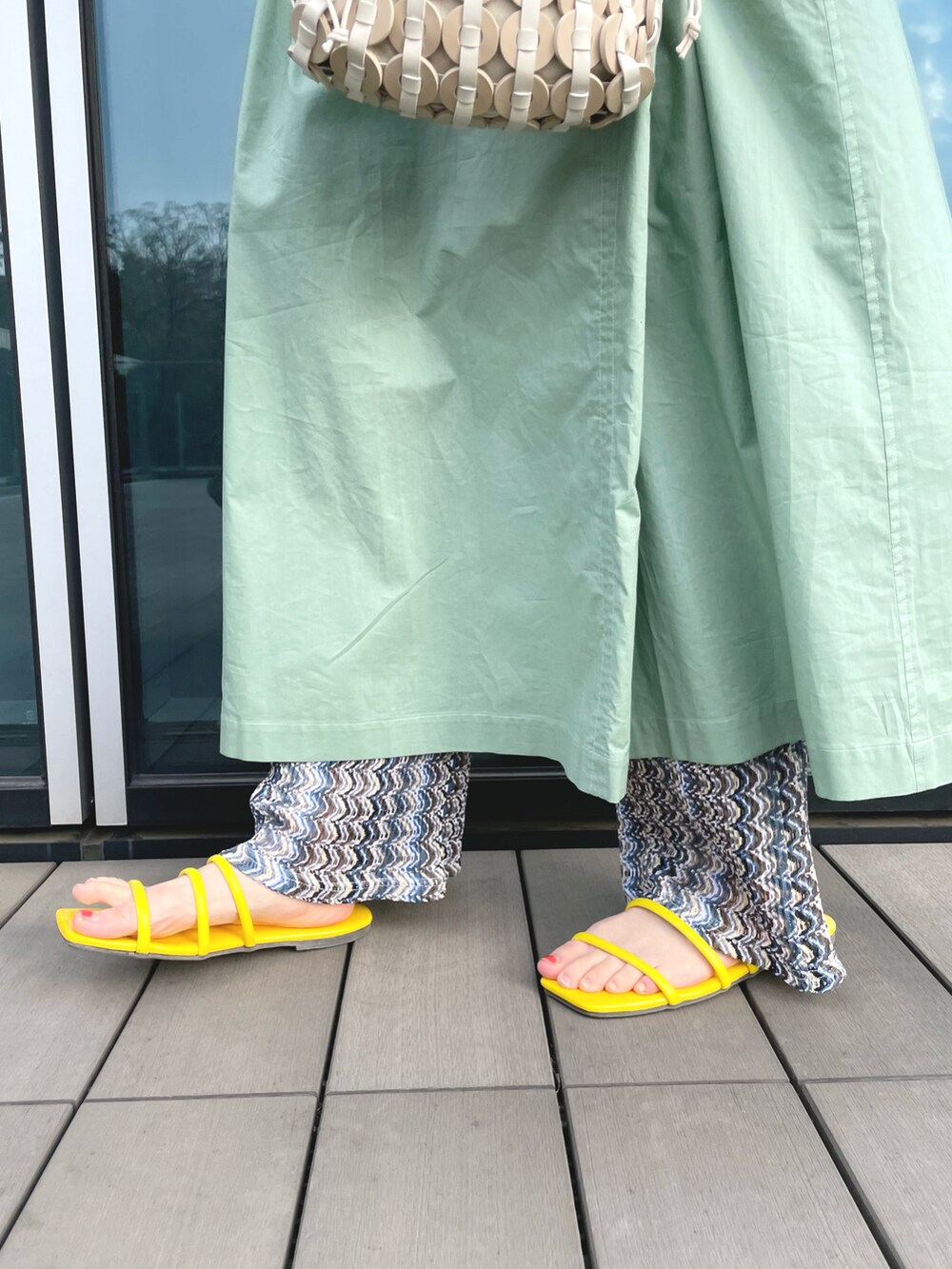 ベージュ系のハンドバッグ、イエロー系のサンダル、グリーン系のワンピースを着用したレディースの春コーディネートの4枚目の写真