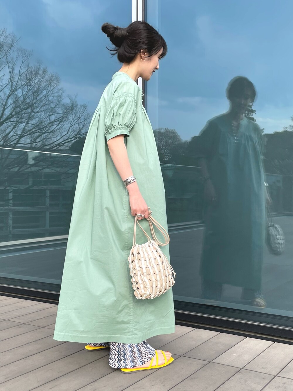 ベージュ系のハンドバッグ、イエロー系のサンダル、グリーン系のワンピースを着用したレディースの春コーディネートの2枚目の写真