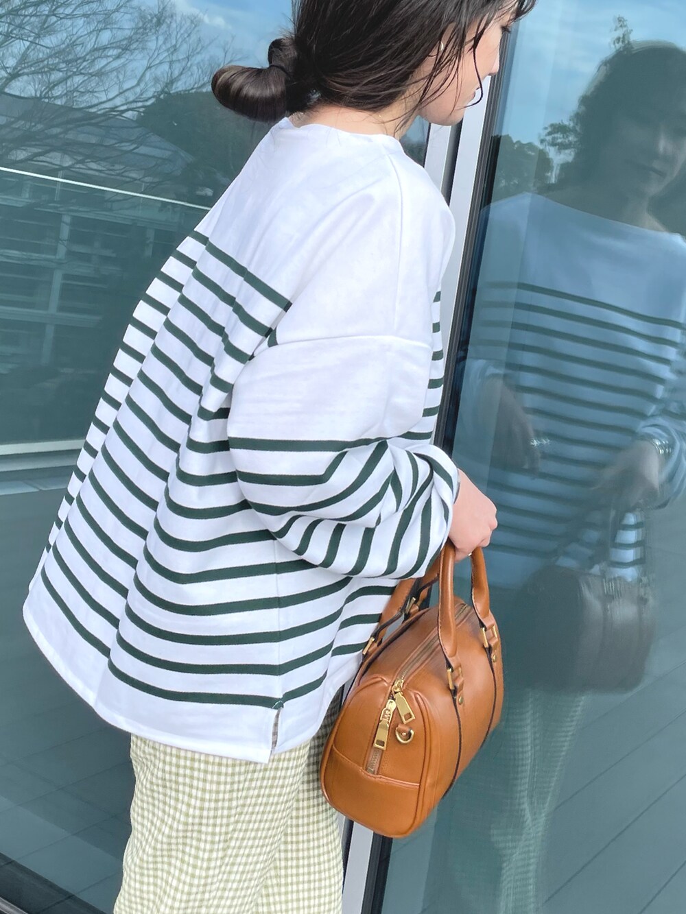 グリーン系のTシャツ/カットソー、ブラウン系のボストンバッグ、ホワイト系のサンダルを着用したレディースの春コーディネートの4枚目の写真