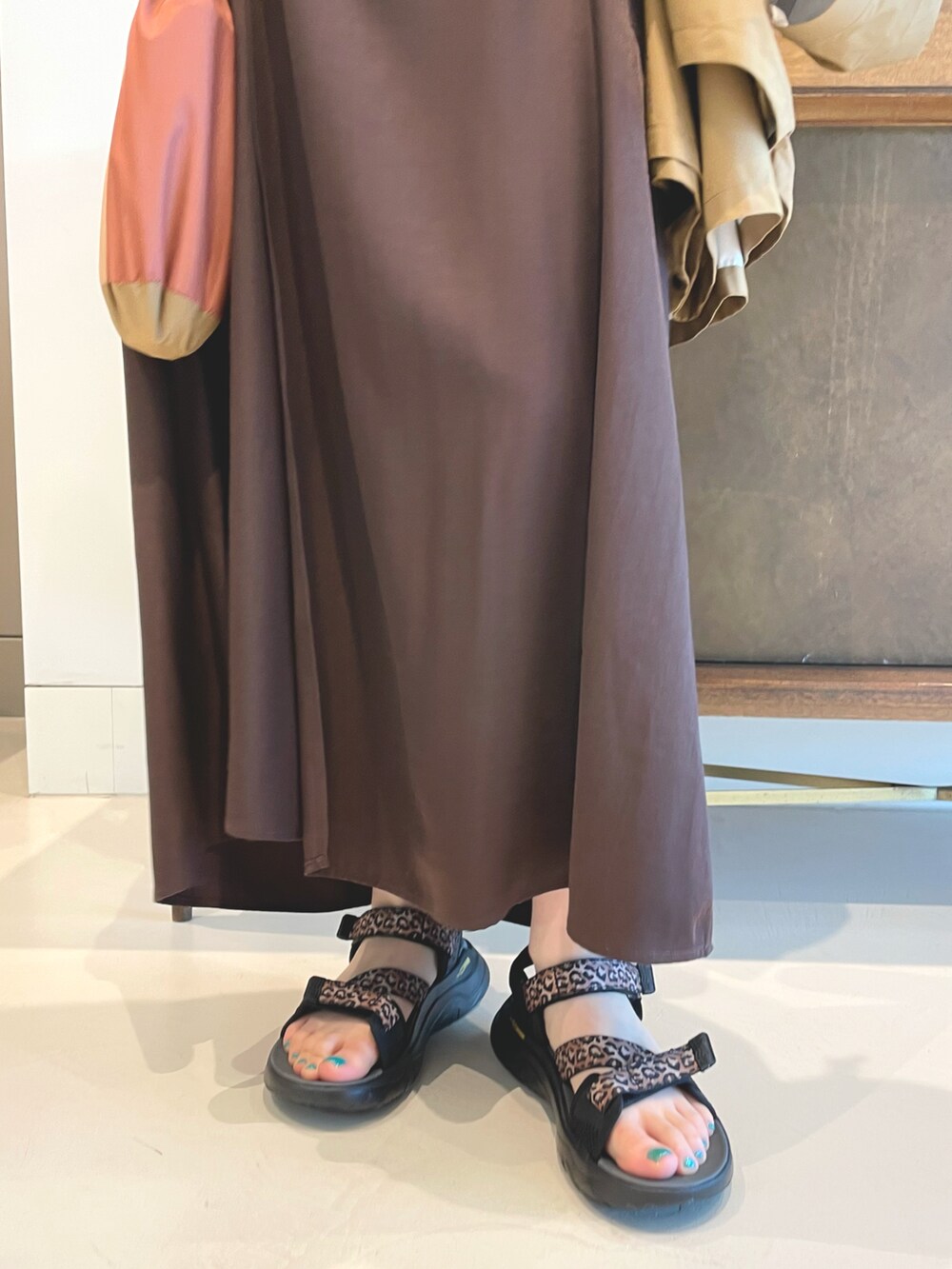 ブラウン系のワンピース、ブラック系のポンチョ、オレンジ系のTシャツ/カットソーを着用したレディースの春コーディネートの4枚目の写真