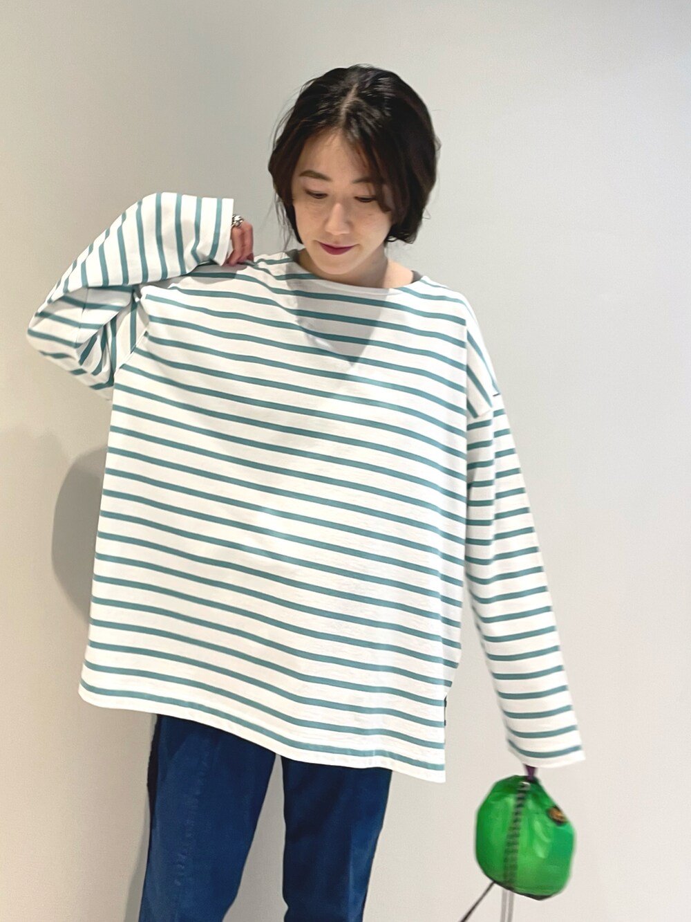 グリーン系のTシャツ/カットソー、グリーン系のトートバッグ、ブルー系のデニムパンツを着用したレディースの春コーディネートの2枚目の写真