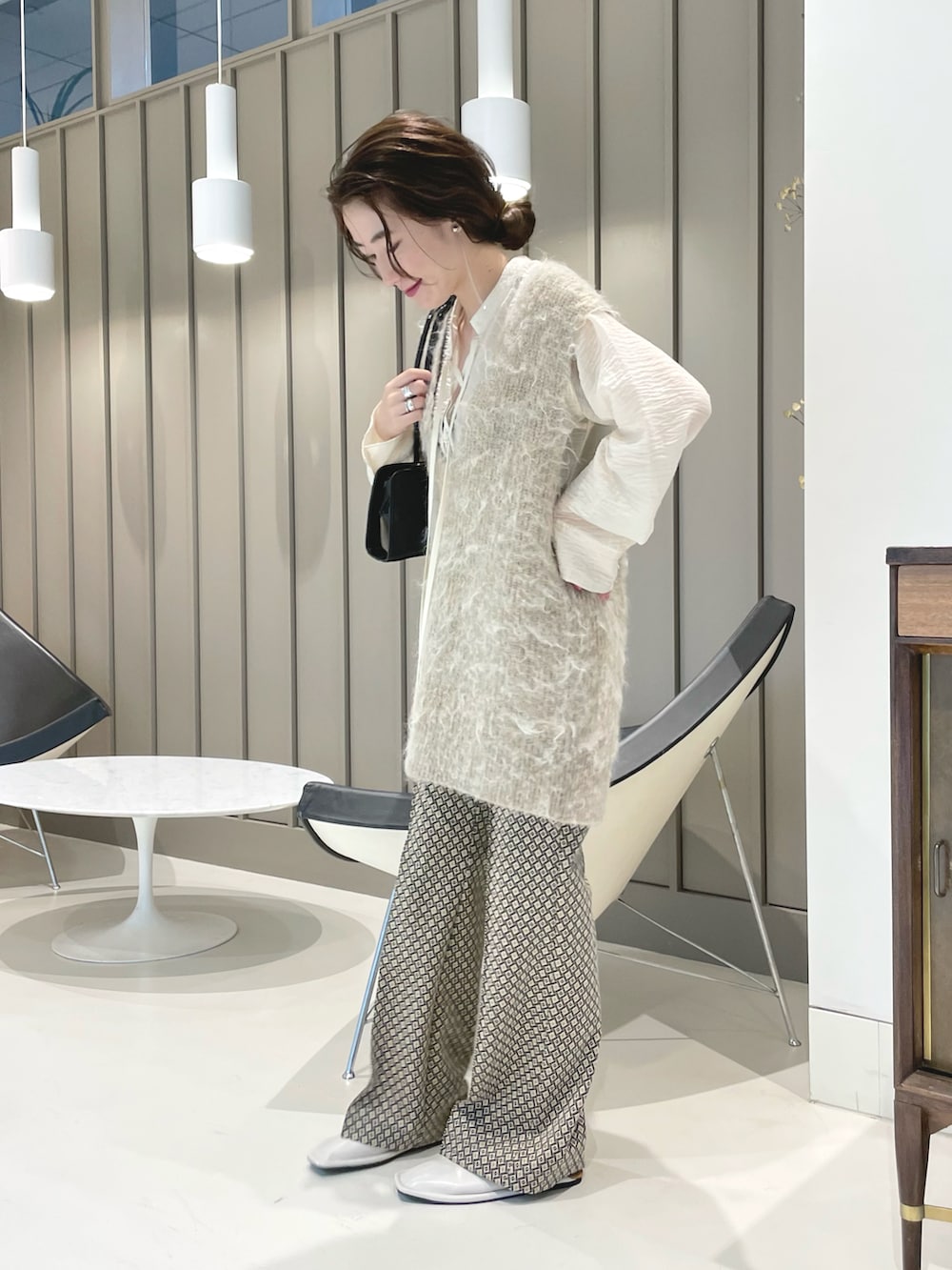 ベージュ系のベスト、ブラック系のトートバッグを着用したレディースの秋コーディネートの2枚目の写真