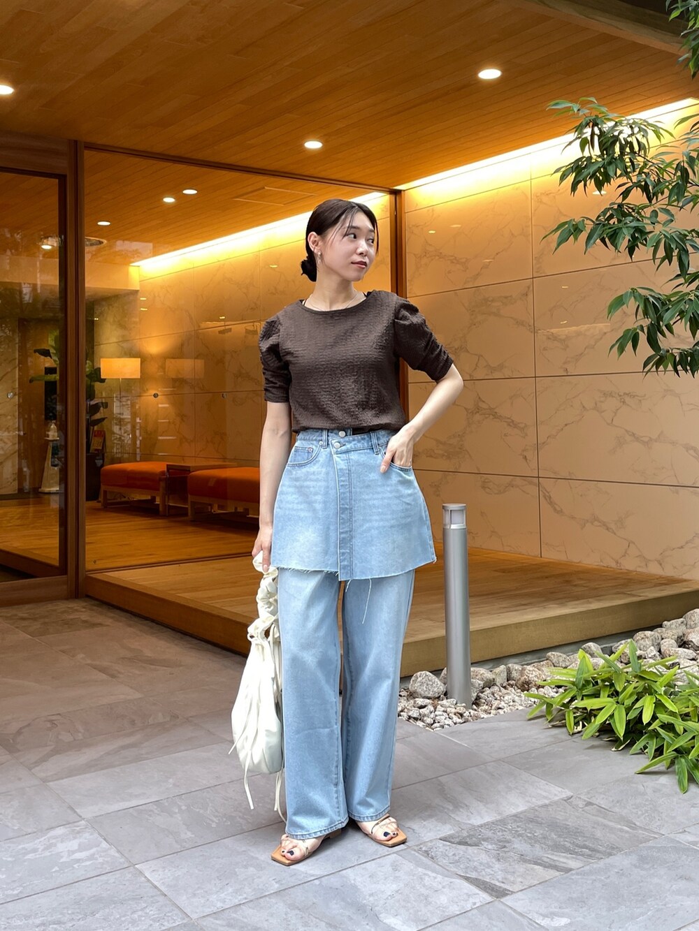 ブラウン系のTシャツ/カットソー、ブルー系のデニムパンツ、その他のサンダルを着用したレディースの夏コーディネートの2枚目の写真
