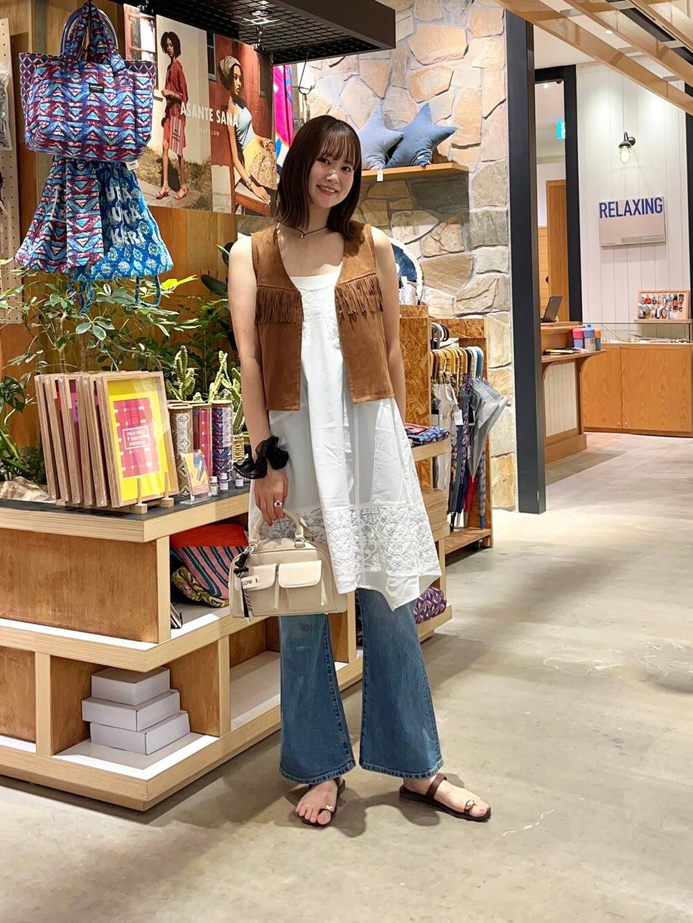 ブラウン系のサンダル、ホワイト系のボストンバッグ、ブルー系のデニムパンツを着用したレディースの夏コーディネートの3枚目の写真