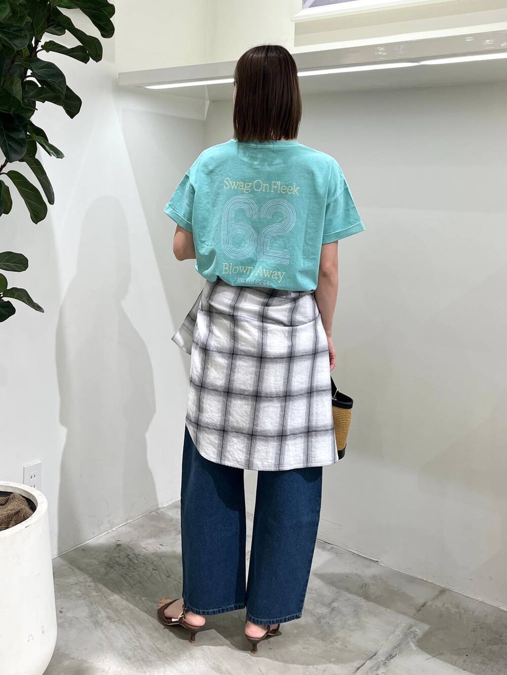 ブルー系のデニムパンツ、グリーン系のTシャツ/カットソー、ブラック系のショルダーバッグを着用したレディースの春コーディネートの3枚目の写真