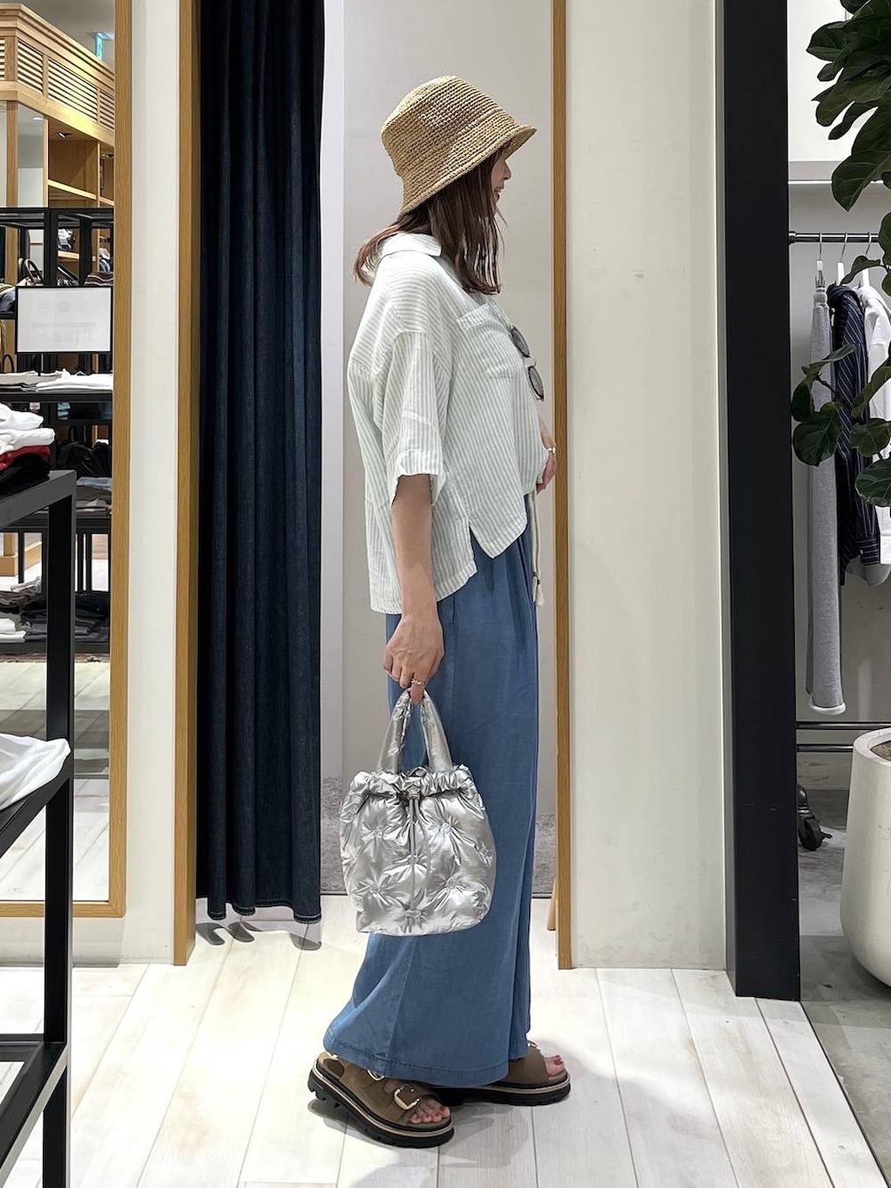ブルー系のデニムパンツ、シルバー系のショルダーバッグ、ベージュ系のサンダルを着用したレディースの春コーディネートの3枚目の写真