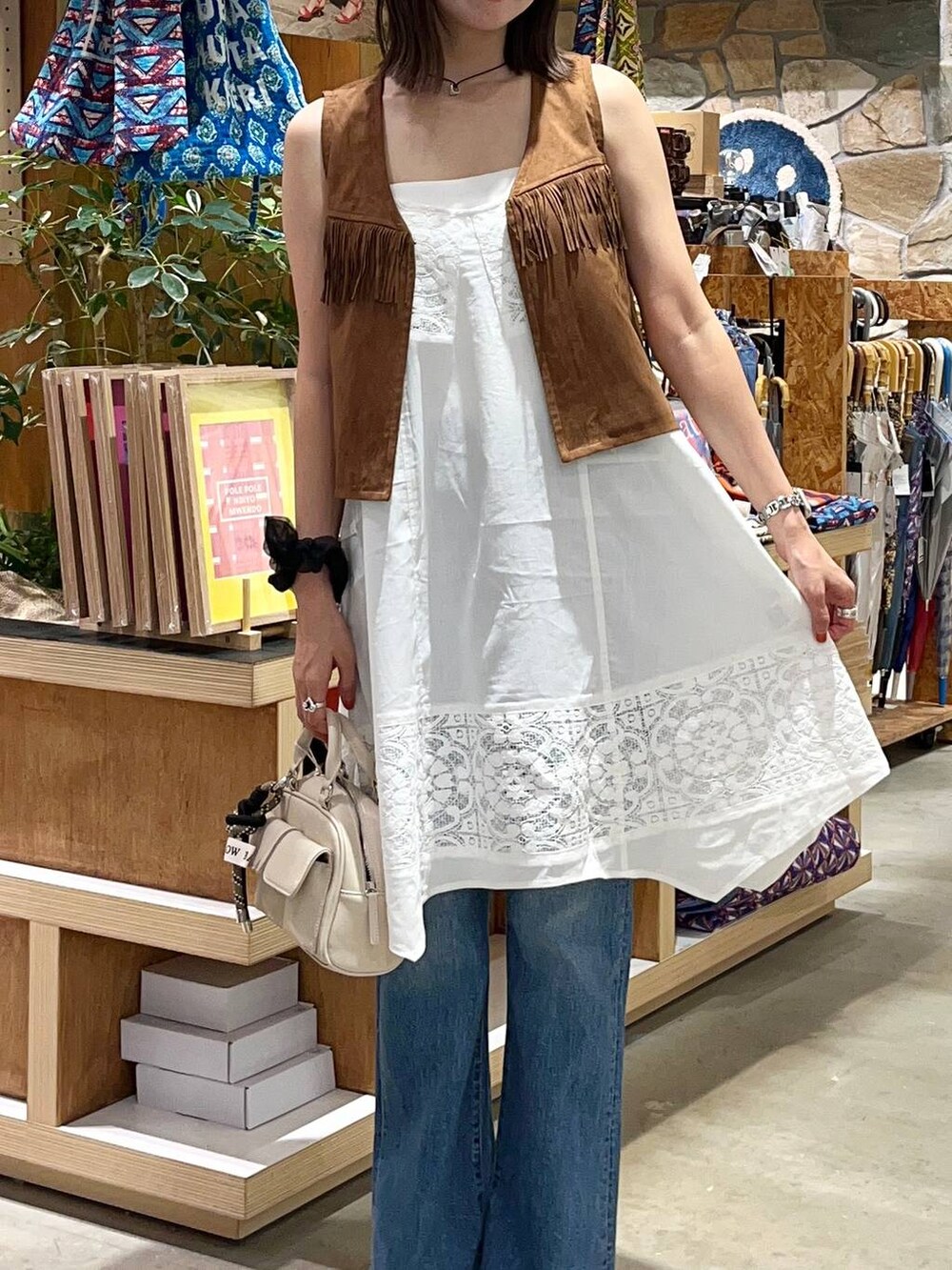 ブラウン系のサンダル、ホワイト系のボストンバッグ、ブルー系のデニムパンツを着用したレディースの夏コーディネートの4枚目の写真