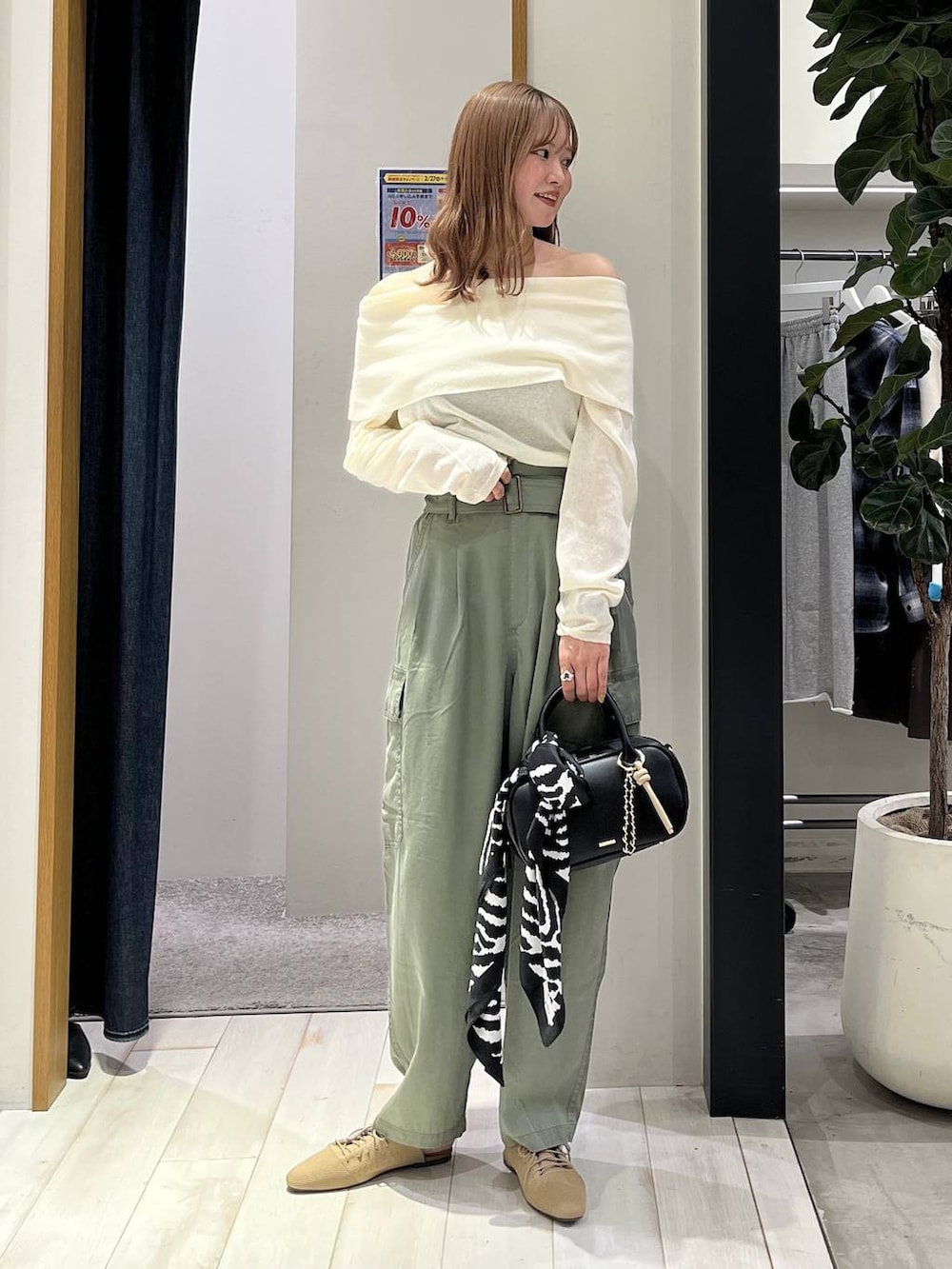 ブラック系のハンドバッグ、ベージュ系のサンダル、グリーン系のカーゴパンツを着用したレディースの春コーディネートの3枚目の写真