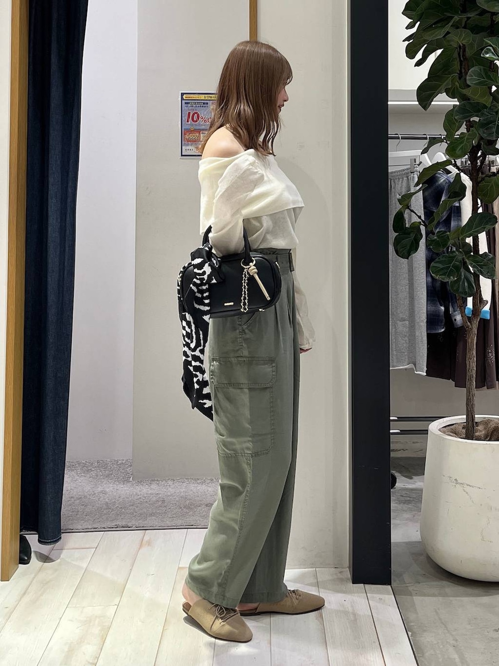 ブラック系のハンドバッグ、ベージュ系のサンダル、グリーン系のカーゴパンツを着用したレディースの春コーディネートの4枚目の写真