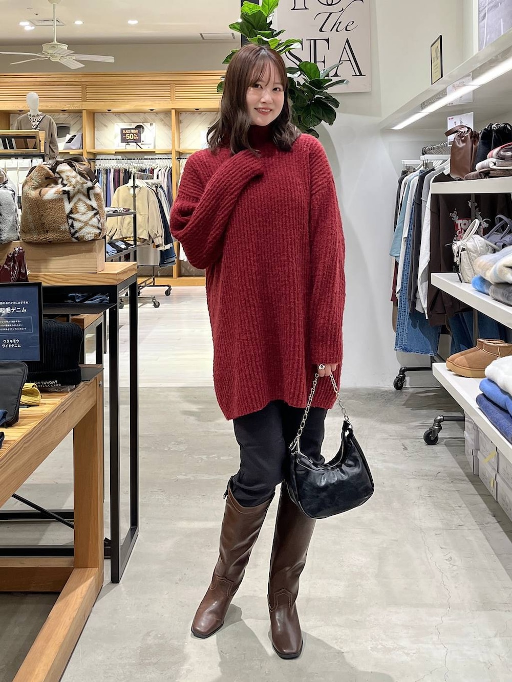 ブラック系のその他パンツ、ブラウン系のブーツ、レッド系のチュニックを着用したレディースの冬コーディネートの2枚目の写真