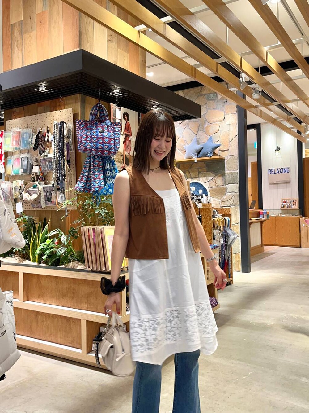 ブラウン系のサンダル、ホワイト系のボストンバッグ、ブルー系のデニムパンツを着用したレディースの夏コーディネートの2枚目の写真