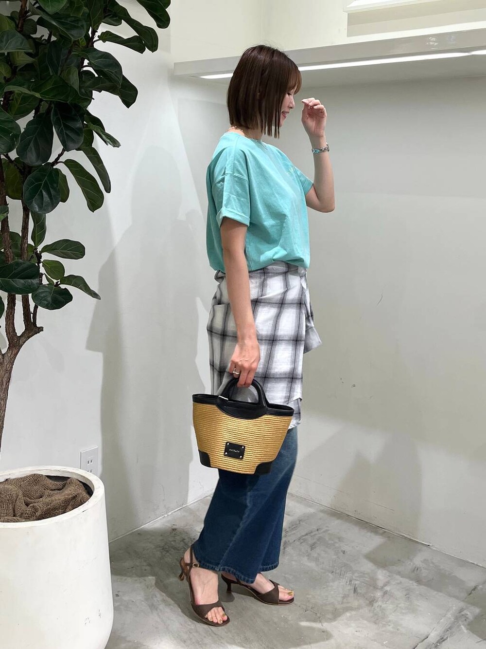 ブルー系のデニムパンツ、グリーン系のTシャツ/カットソー、ブラック系のショルダーバッグを着用したレディースの春コーディネートの2枚目の写真