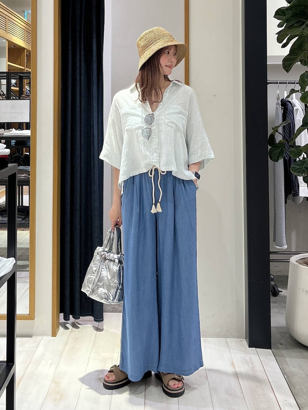 ブルー系のデニムパンツ、シルバー系のショルダーバッグ、ベージュ系のサンダルを着用したレディースの春コーディネートの2枚目の写真