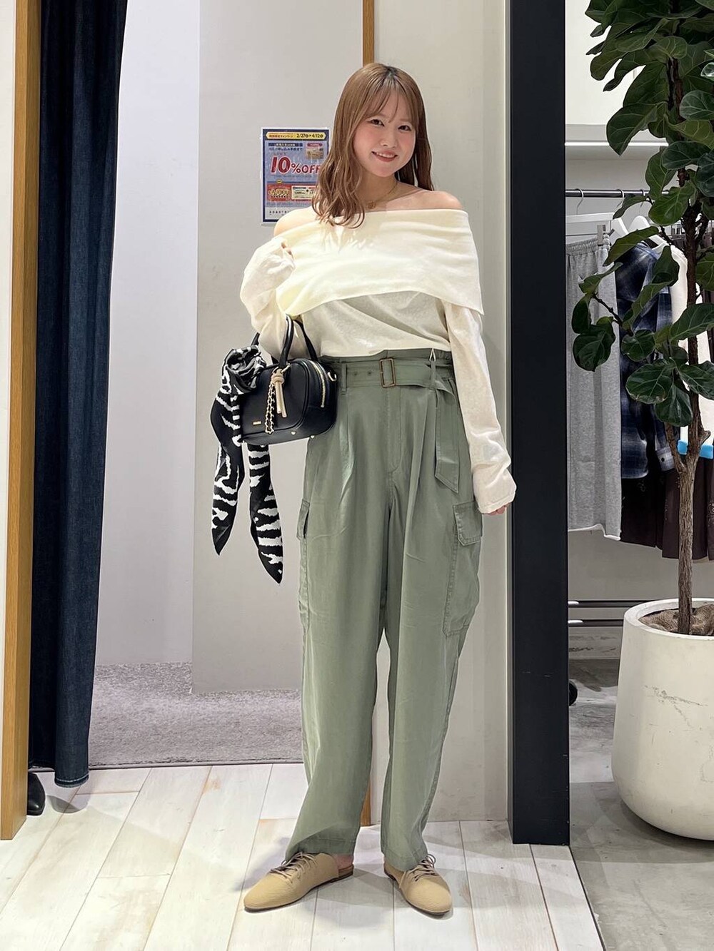 ブラック系のハンドバッグ、ベージュ系のサンダル、グリーン系のカーゴパンツを着用したレディースの春コーディネートの2枚目の写真
