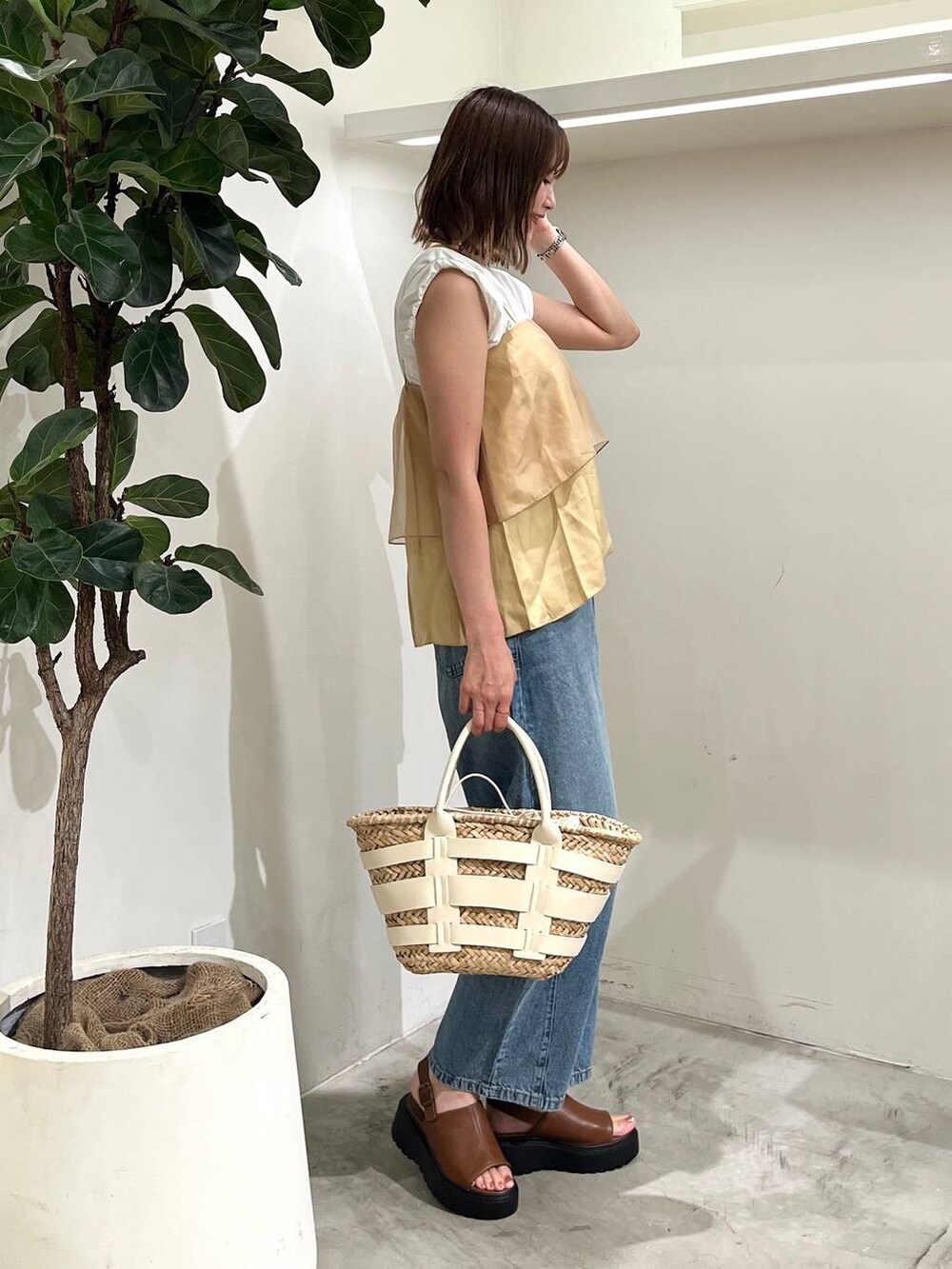 ホワイト系のかごバッグ、ブルー系のデニムパンツ、ホワイト系のTシャツ/カットソーを着用したレディースの夏コーディネートの2枚目の写真