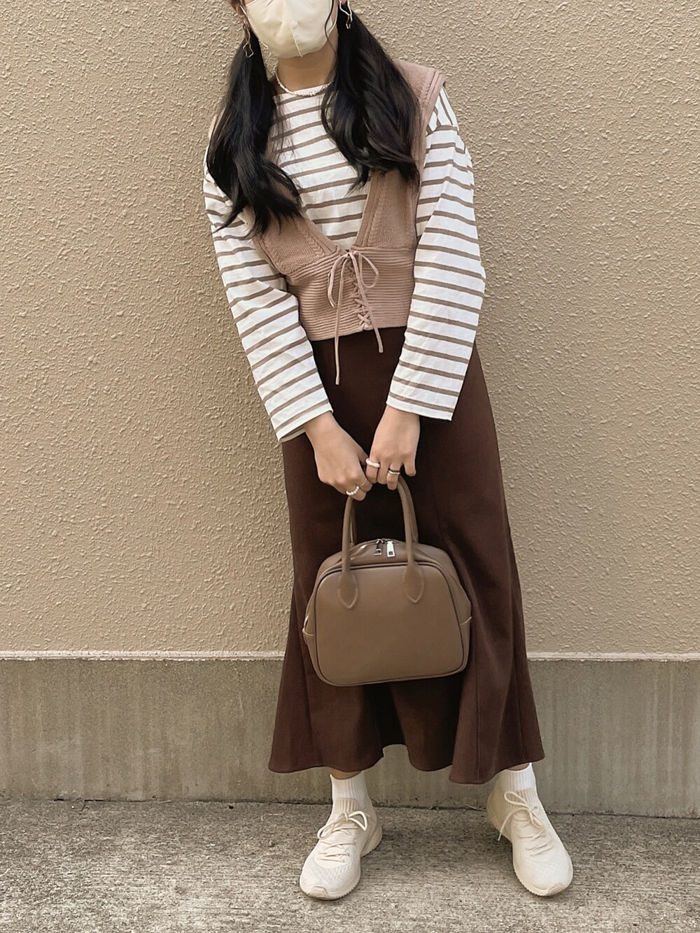 ベージュ系のショルダーバッグ、ホワイト系のTシャツ/カットソー、ベージュ系のベストを着用したレディースの春コーディネートの2枚目の写真