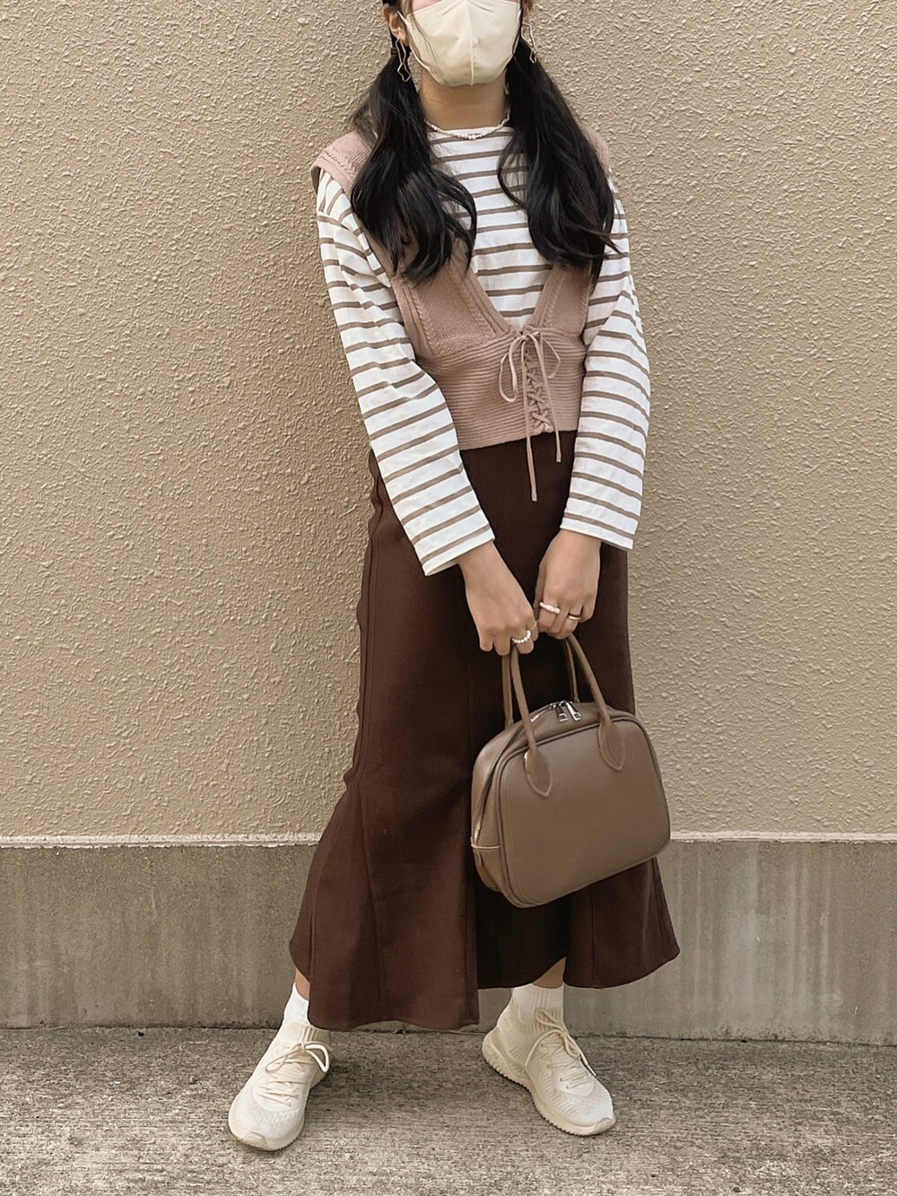 ベージュ系のショルダーバッグ、ホワイト系のTシャツ/カットソー、ベージュ系のベストを着用したレディースの春コーディネートの3枚目の写真